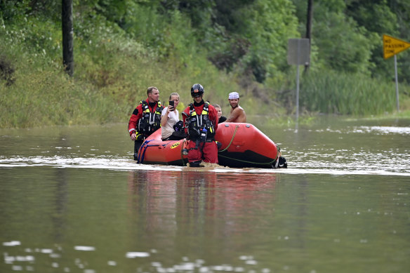 Members of the Winchester Fire Department walk inflatable boats across floodwaters.