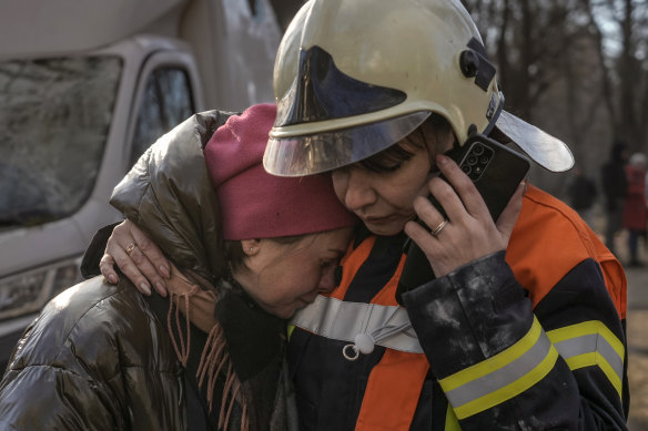 A firefighter comforts a woman outside a destroyed apartment building after a bombing in a residential area in Kyiv, Ukraine, on Tuesday.