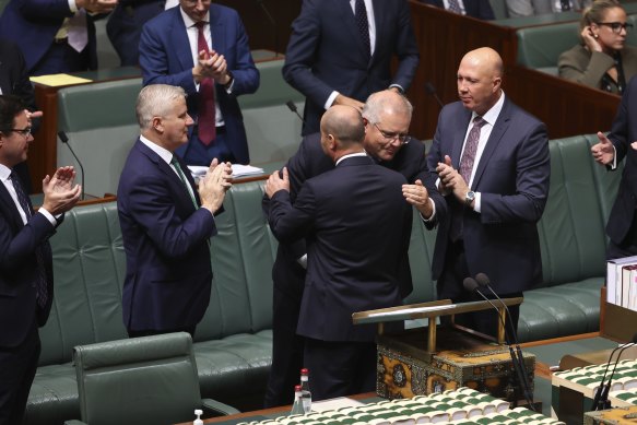 Treasurer Josh Frydenberg is congratulated by Prime Minister Scott Morrison and colleagues after delivering the Budget speech.