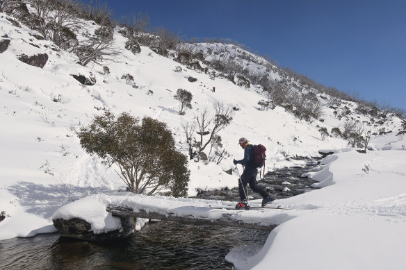 Crossing the Guthega River, skiing and snowboarding in the Australian alpine backcountry, the Snowy Mountains main range.