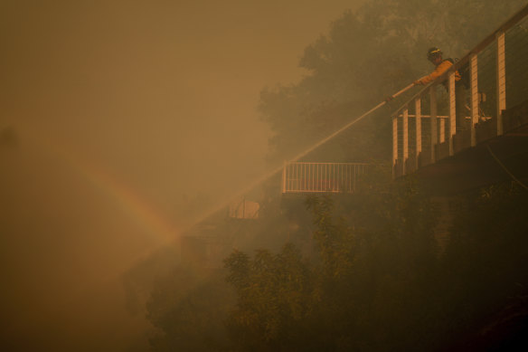 A firefighter battles the Palisades Fire from a deck in Mandeville canyon on Saturday (LA time).