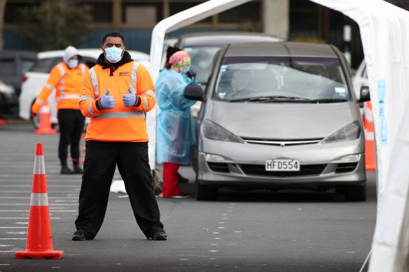 A security guard poses for a photograph as nurses test people arriving at a COVID-19 testing facility in Otara, Auckland.