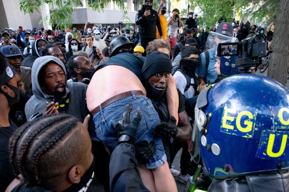 A group of men carry an injured man away after he was allegedly attacked by some of the crowd of protesters as police try to intervene on the Southbank near Waterloo station.