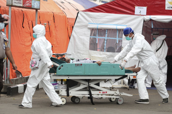 Paramedics roll a man on a hospital bed past emergency tents erected to accommodate a surge of COVID-19 patients at a hospital in Bekasi, on the outskirts of Jakarta.