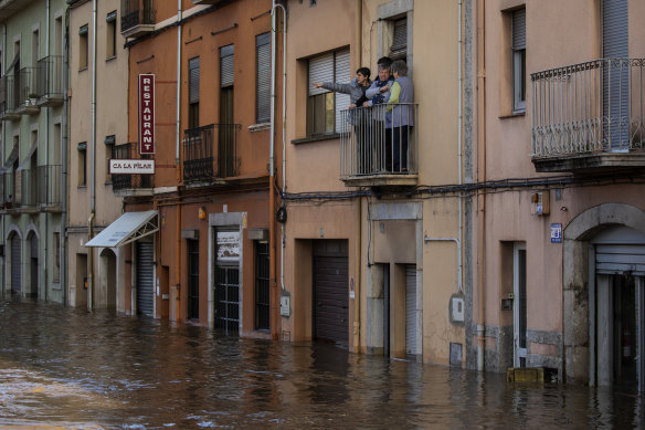 People stand on a balcony following a storm in Girona, Spain. At least 11 have died and five people remain missing.