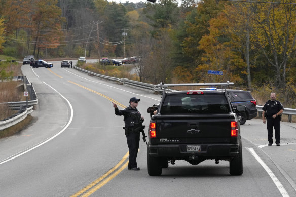 Police officers speak with a motorist at a roadblock in Lisbon, Maine.