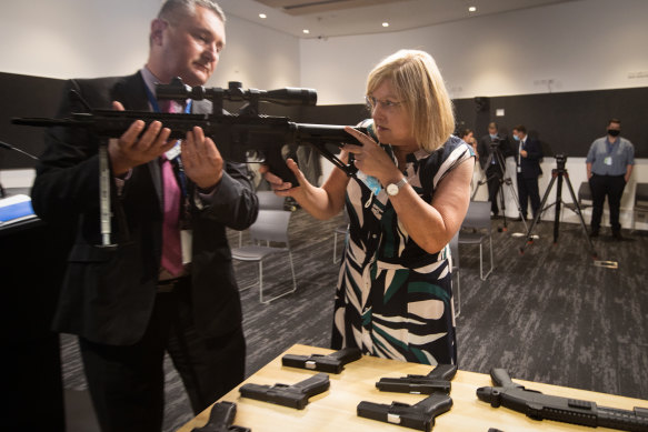 Detective Inspector Mick Daly shows Police Minister Lisa Neville an illegal guns seized by police during the launch of the illicit firearms unit in Melbourne. 