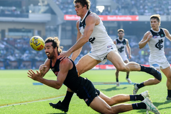 Alex Pearce of the Dockers handballs under pressure from Charlie Curnow of the Blues.