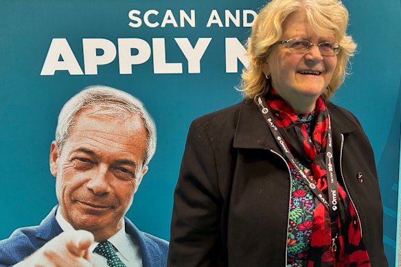 Susan Morrell, who believes migration is a key problem, in front of a poster of Farage urging members to consider standing for election for the party.