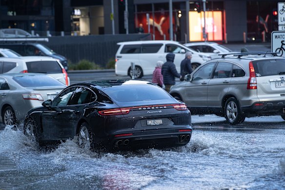 Cars drive through water at the intersection of Lorimer Street  and Wurrundjeri Way in central Melbourne.