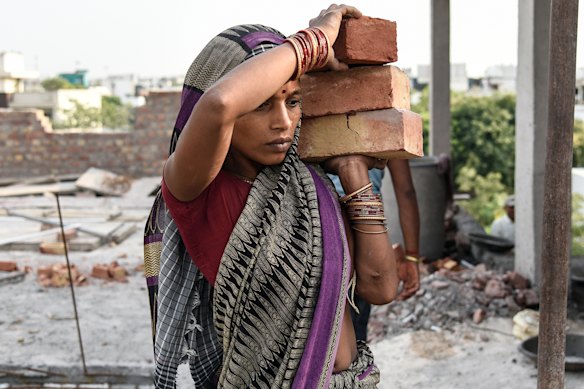 A woman carries bricks at a construction site on a hot summer evening in New Delhi.