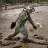 Rescue personnel walk over a sea of mud near an orchard in Nagano, Japan.