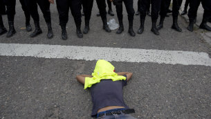 A Honduran migrant rests at the feet of Guatemalan police.