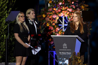 Summer Warne speaks on stage alongside Jackson Warne and Brooke Warne during the memorial.