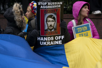 Supporters of Ukrainian sovereignty protest the Russian invasion with banners likening President Putin to Hitler.