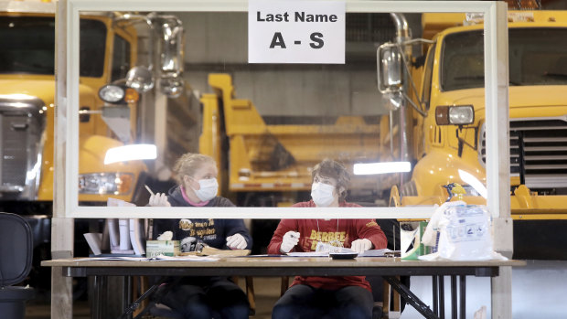 Sisters Kelly and Teal Rowe work behind a plexiglass barrier while waiting to verify voters at the town's highway garage facility in Dunn, Wisconsin.
