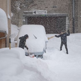 Children remove snow from a car in the the village of Andermatt, Switzerland on Sunday.
