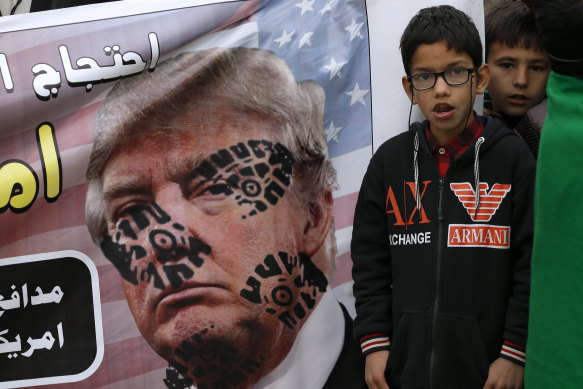 A boys next to a desecrated poster of US President Donald Trump during a rally  to condemn the killing of Iranian Revolutionary Guard General Qassem Soleimani.