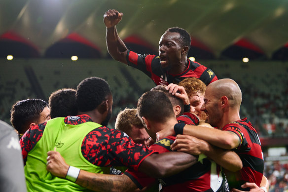 Tate Russell is mobbed by his teammates after scoring Western Sydney’s first goal.