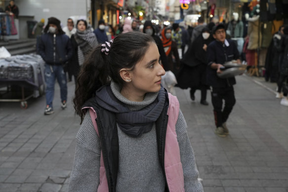 A woman walks around a commercial district without wearing her mandatory Islamic headscarf in downtown Tehran.