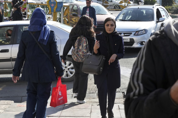 A young Iranian woman crosses a street without wearing her mandatory Islamic headscarf in Tehran in November.