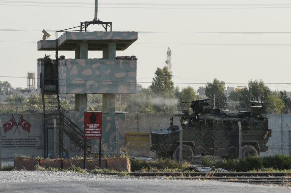 A Turkish military armoured vehicle fires towards the Syrian town of Tal Abyad from the Turkish side of the border. 