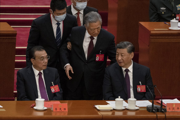 Eski Çin Devlet Başkanı Hu Jintao, kendisine Kongre'den götürülürken Başbakan Li Keqiang (solda) ve Başkan Xi Jinping ile konuşmaya çalışıyor.