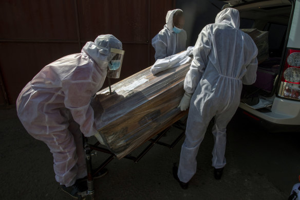 Funeral home workers in protective suits carry the coffin of a woman who died from COVID-19 into a hearse in Katlehong, near Johannesburg.