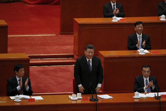 Party officials applaud as Chinese President Xi Jinping, standing, delivers his speech on the 70th anniversary of the Chinese army entering North Korea to resist the US army.