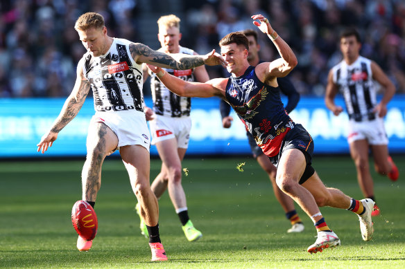 Star Magpie Jordan De Goey kicks while being tackled by Crow Ben Keays.