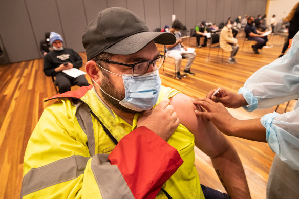 A man rolls up his sleeve to get jabbed at a vaccine clinic in Hoppers Crossing.