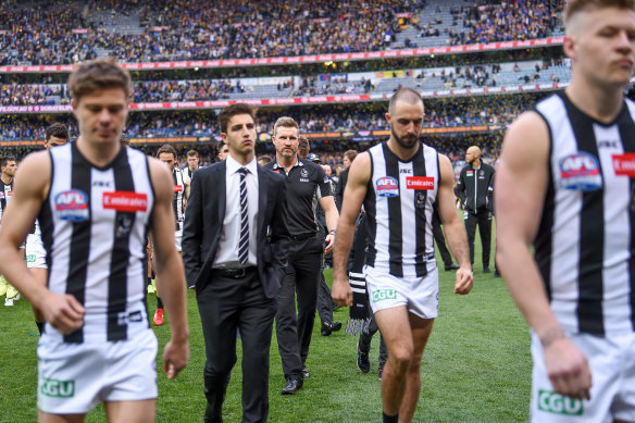 A dejected Steele Sidebottom (second from right) leaves the field with his Pies teammates.
