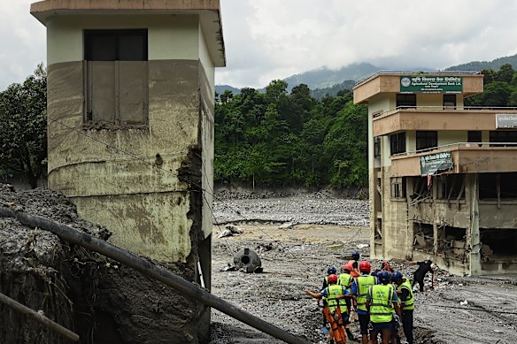 Nepalese police and rescue workers pick their way through quicksand to search for bodies.