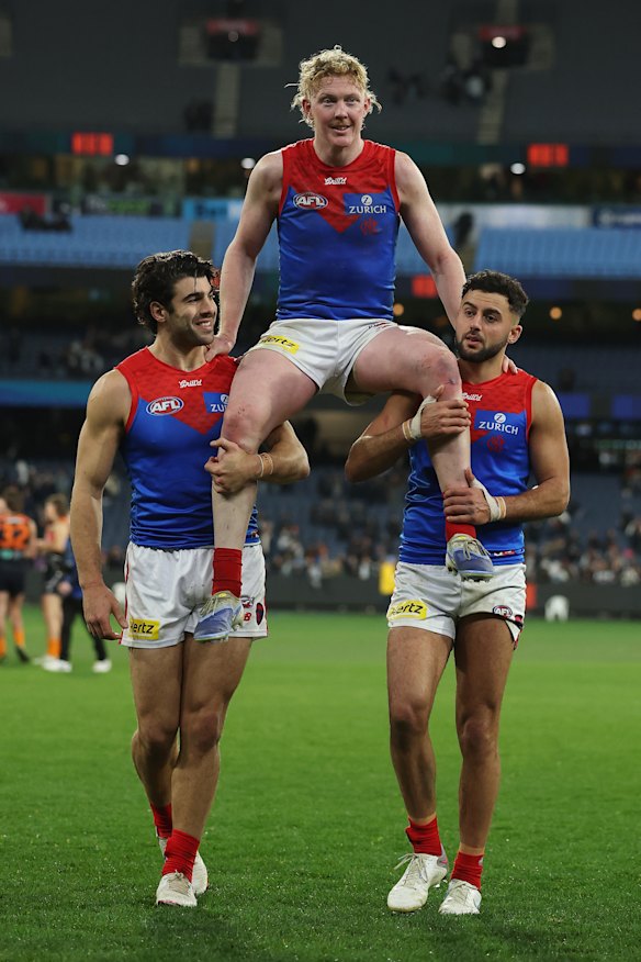 Clayton Oliver (centre) was chaired off after his 200th game by Christian Petracca (left) and Christian Salem (right).