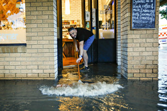 The Corner cafe owner Saad El Amin sweeps floodwater out of his premises on the shopping strip on Hamilton Street in Gisborne.