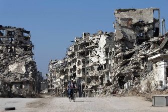 A Syrian boy rides a bicycle through a part of the old city of Homs, devastated  by the Assad regime bombings.