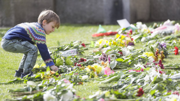 A child lays flowers outside Windsor Castle, where Prince Philip died.