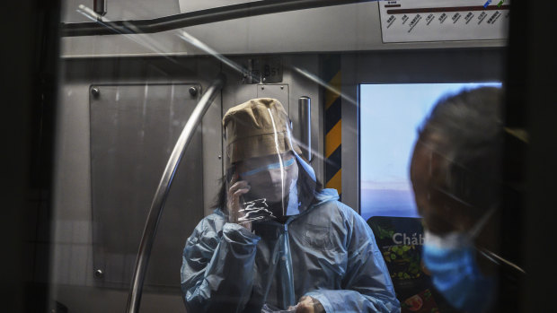 A woman wears a protective mask and face shield as she rides the subway in Beijing.