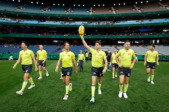 AFL umpires walk onto the MCG.