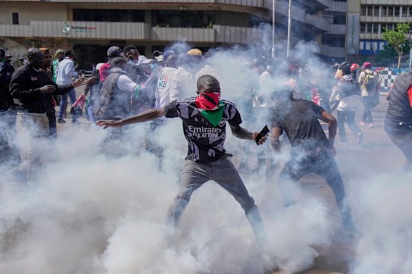 Protesters scatter as police fire tear gas.
