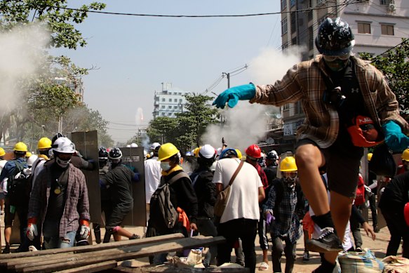 Protesters are dispersed as riot police fired tear gas behind a makeshift barricade in Yangon.