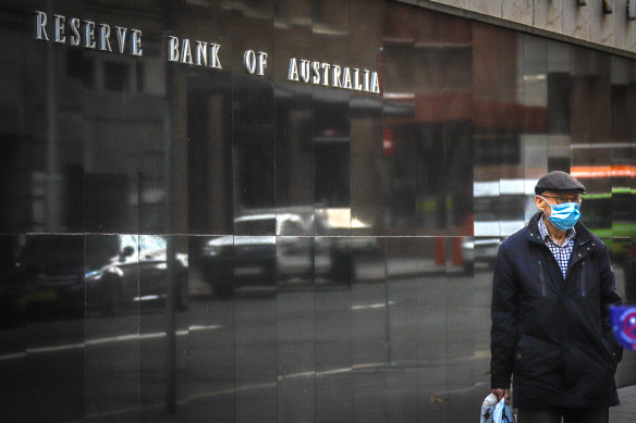 A pedestrian wearing a face mask walks past the Reserve Bank of Australia.