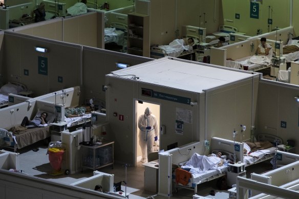 A medical worker wearing protective gear enters the treatment hall of a temporary hospital for coronavirus patients in the Krylatskoye Ice Palace in Moscow, Russia, where the health system has been overwhelmed by the coronavirus.