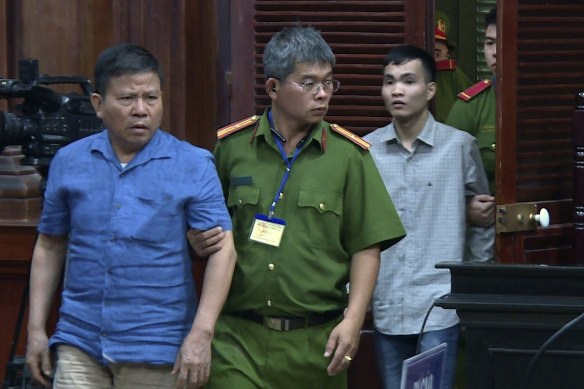 Chau Van Kham (left) being escorted into a Vietnamese courtroom in 2019.