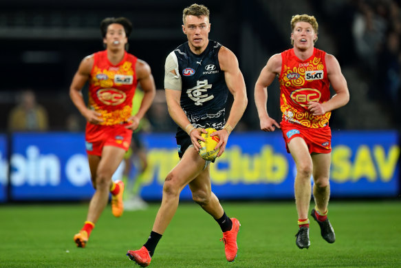 Patrick Cripps (centre) shows a clean set of heels to his Gold Coast opponent Matt Rowell (right).
