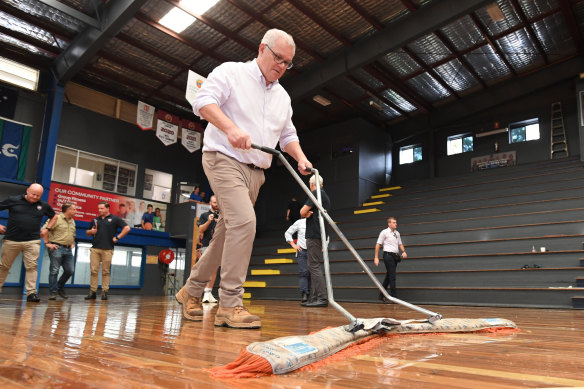 I do hold a mop: Prime Minister Scott Morrison dries a flood-damaged court in Brisbane on Thursday. 