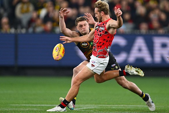 Darcy Parish of the Bombers kicks whilst being tackled by Jacob Hopper of the Tigers.