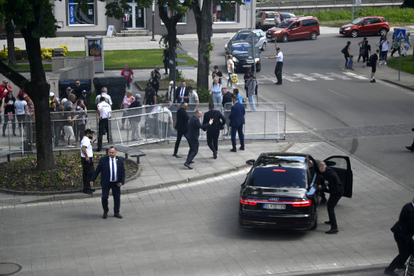 Bodyguards take Slovak Prime Minister Robert Fico in a car from the scene of the shooting.