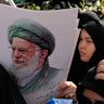 Mourners gather around the flag-draped coffins of Iranians killed in Israeli strikes, as one of them holds a poster of the Supreme Leader Ayatollah Ali Khamenei, in Tehran.