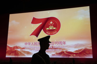 A Chinese paramilitary policeman is silhouetted by a display showing the upcoming 70th anniversary of the Founding of the People's Republic of China in Beijing.
